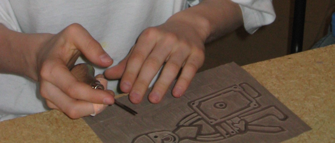 Das Foto zeigt Kinderhände beim Bearbeiten einer Linolplatte. Die rechte Hand hält ein Schabeisen. Auf der Platte sind die Umrisse eines Ritters in reduzierten Formen zu sehen.
